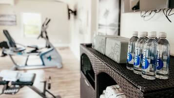 A home gym with exercise equipment, a television, and water bottles on a shelf.