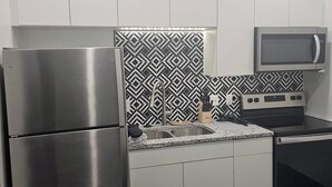 Eine moderne Küche mit Edelstahlgeräten, einer Mikrowelle und einer strukturierten Spritzschutzwand.