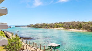 A coastal view with clear turquoise waters, a wooden dock, and a beach with sparse vegetation. - Creekfront Kingscliff Waters 5 (Kingscliff)