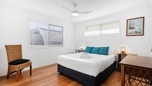 A bedroom with a bed, a chair, a table, and a ceiling fan. - Creekfront Kingscliff Waters 5 (Kingscliff)