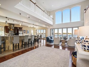 A spacious open-plan living area with a kitchen, dining area, and seating space. - Bayfront Retreat | Sleeps 16 | Pool + Beach Access (Bethany Beach)