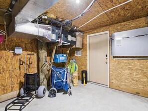 A utility room with exposed ductwork, a ladder, a blue cart, and a white door. - Coastal Escape w/ Views | Steps from Bethany Beach (Bethany Beach)