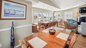 A spacious dining area with a wooden table, chairs, and a view of the outdoors. - Steps to Bethany Beach | Luxury Ocean Block Home (Bethany Beach)