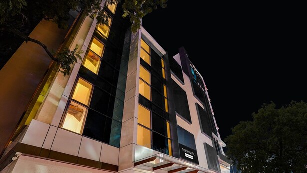 A modern hotel with a prominent 'TOWNHOUSE' sign, large windows, and a well-lit facade.