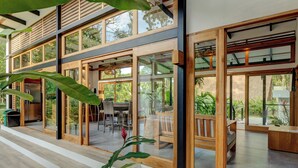 A modern house with large glass doors leading to a patio area with outdoor furniture. - Villa Opalo (Cahuita)