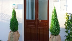 Una puerta doble de madera con paneles de vidrio, una pequeña luz adosada a la pared y una placa con el número 219.