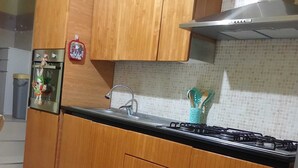 Una cocina con gabinetes de madera, un refrigerador de acero inoxidable, una estufa a gas y un salpicadero de azulejos.