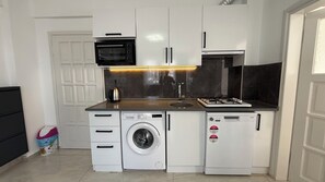 Een minikoelkast, een kookplaat, kookgerei, borden en bestek