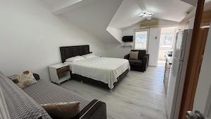A bedroom with a bed, bedside table, chair, and a view of the outside. - Elitaş Apart Otel (Fethiye)