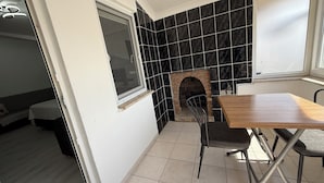 A small kitchen with a black tiled backsplash, a wooden table, and a chair. - Elitaş Apart Otel (Fethiye)