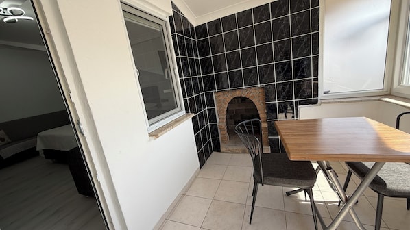 A small kitchen with a black tiled backsplash, a wooden table, and a chair. - Elitaş Apart Otel (Fethiye)