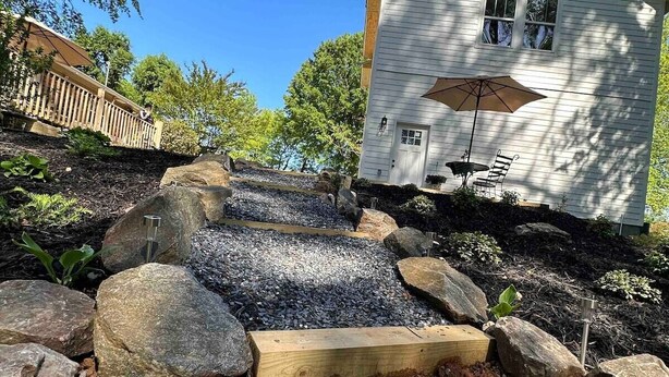 A white house with a porch and a small garden area with rocks and plants. - The Loft (Kennesaw)