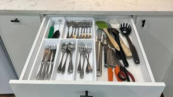 Una cocina con una cafetera Keurig, una caja de café con la etiqueta 'Homebrew & Co. Coffee House', y un cajón que contiene varios utensilios y herramientas de cocina.