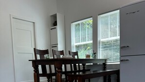 A modern kitchen with a dining table, chairs, and a refrigerator. - The Loft (Kennesaw)