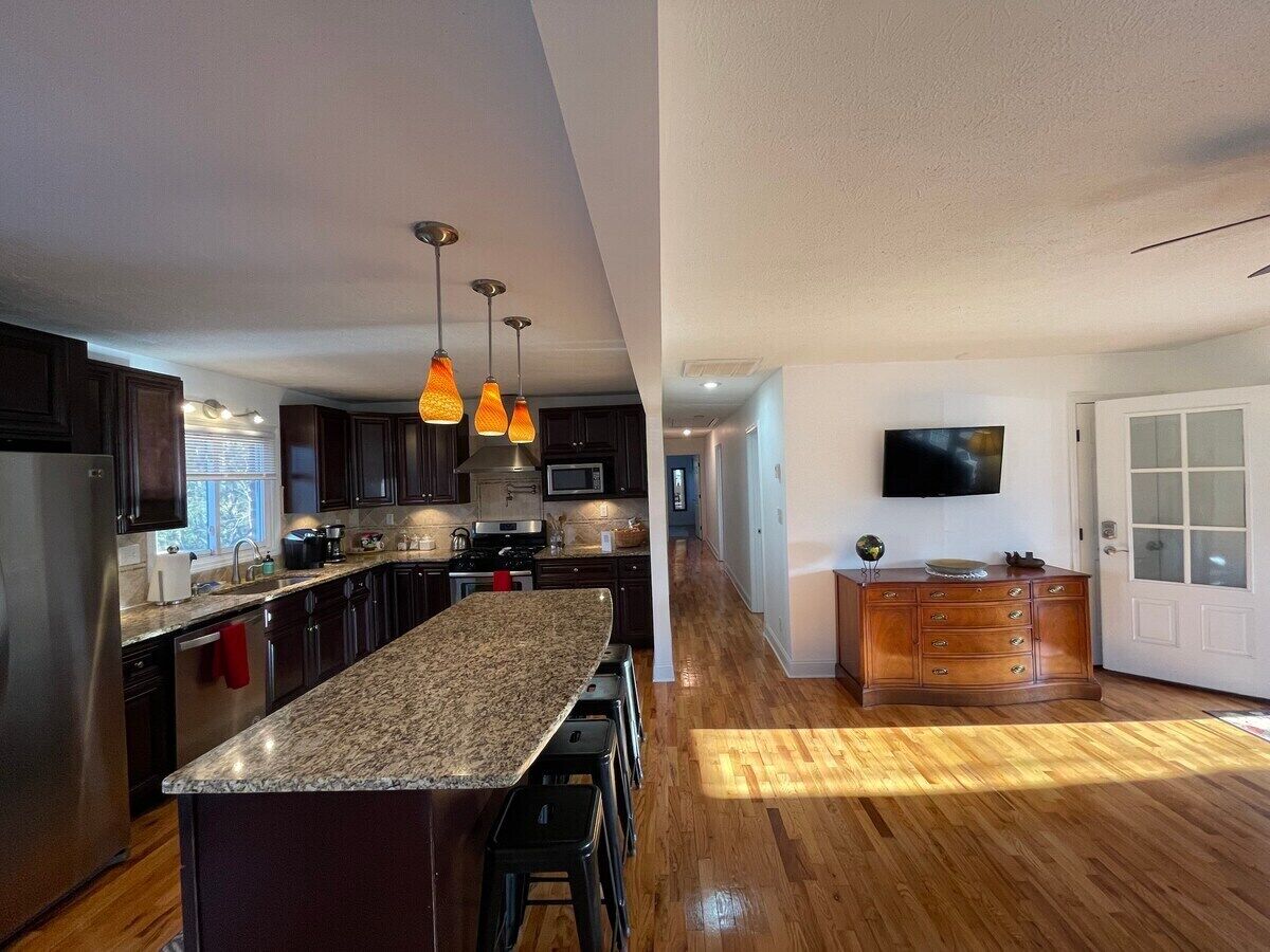 Una cocina moderna con encimeras de granito, electrodomésticos de acero inoxidable y suelo de madera.