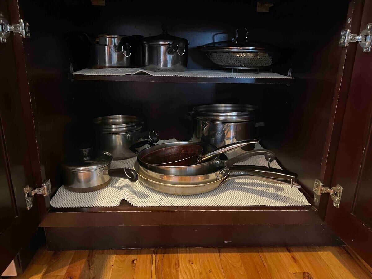 Un meuble en bois doté d’étagères où sont rangés divers ustensiles de cuisine et ustensiles de cuisson.