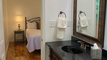 A bathroom with a wooden vanity, a large mirror, and a sink. There is a towel rack with two towels and a tissue box on the vanity.