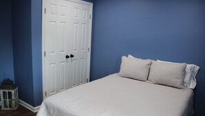 A bedroom with a bed, a white door, and a blue wall. - NEW Two Bedroom Suite Nestled in Stunning Backyard Garden (Athens)
