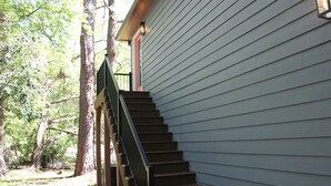 A wooden staircase leading to a house with a light-colored exterior wall. - NEW Two Bedroom Suite Nestled in Stunning Backyard Garden (Athens)