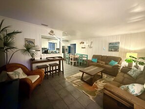 A living room with a sofa, coffee table, and a dining area with chairs and a table. - Blue Seahorse Coastal Retreat 3BR/2BA pet friendly, privacy fenced yard (Rockport)