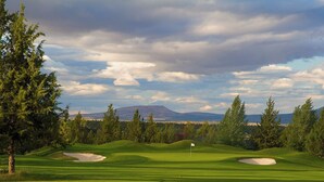 A golf course with a flag on the green, trees, and a mountain in the background. - Eagle Crest Retreat | 6 Resort Passes Included (Redmond)