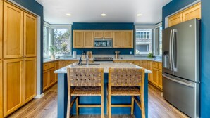 A modern kitchen with wooden cabinets, a stainless steel refrigerator, and a central island with seating. - Eagle Crest Retreat | 6 Resort Passes Included (Redmond)