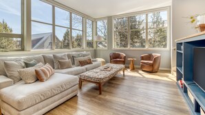 A spacious living room with a large window, a sofa, a coffee table, and a television. - Eagle Crest Retreat | 6 Resort Passes Included (Redmond)