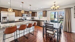 Een moderne keuken met een centraal eiland, barstoelen en een eettafel.