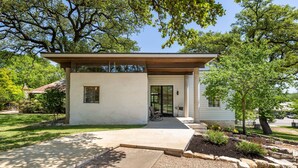 Une maison moderne avec un toit plat, un porche à l’avant et un jardin bien entretenu.