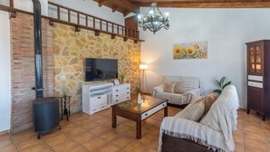 Ein gemütliches Wohnzimmer mit Steinwand, Kamin, Fernseher, Sofa und Schrank.