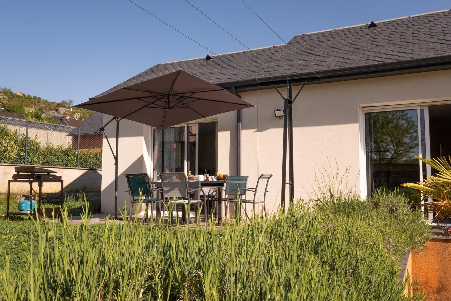 A patio with a table and chairs, an umbrella, and a gas cylinder.