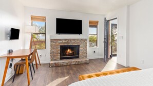 A modern room with a fireplace, a flat-screen TV, a dining area, and a bed. - Private and Quiet with stunning views (Tucson)