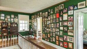 A room with a wooden staircase, green walls, and a wall covered with framed photographs. - Higganum House B&B (Higganum)