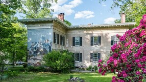 A historic building with a mural, a well-maintained lawn, and vibrant pink flowers. - Higganum House B&B (Higganum)