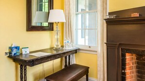 A room with a wooden bench, a table with a lamp, a mirror, and a fireplace. - Higganum House B&B (Higganum)