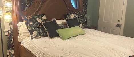 Une chambre à coucher avec un lit en bois, des rideaux à motifs floraux et une lampe de chevet.