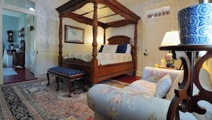 A four-poster canopy bed with a matching bench, a floral sofa, and a traditional lamp. - The Gallery (Hermann)