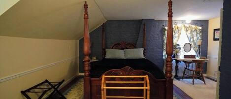 A bedroom with a four-poster bed, a wooden ladder, a desk with a chair, and a mirror.