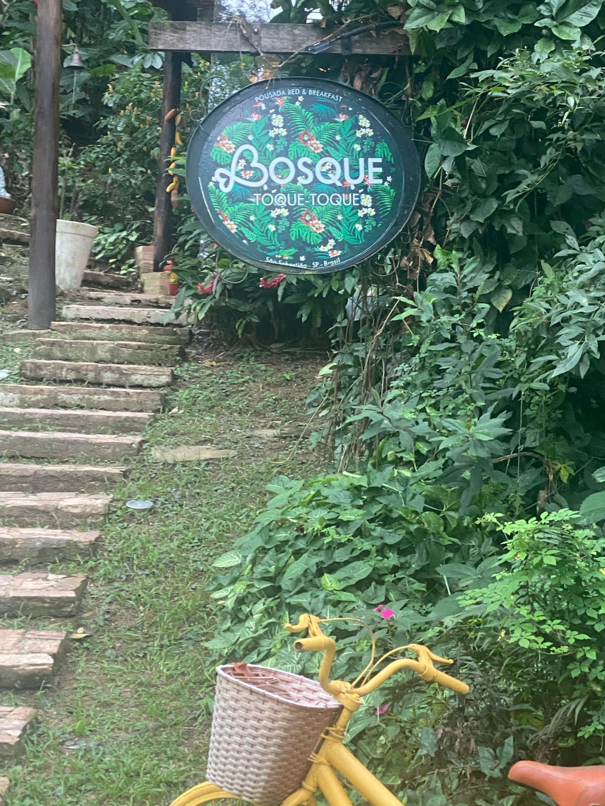 Un jardín con un cartel que indica Bosque Toque Toque, una pousada y bed and breakfast en São Sebastião, SP, Brasil.