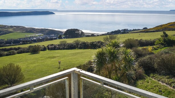 A coastal landscape with a view of the sea, grassy fields, and a distant town. - 2 bedroom accommodation in Woolacombe (Woolacombe)