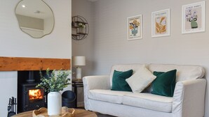 Ein Wohnzimmer mit einer Couch, einem runden Holztisch, einem Kamin und Wandbildern.