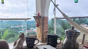 A person relaxing on a sofa with a view of a lush landscape. - Encantadora casa de 4 alcobas con WIFI (Tocaima)