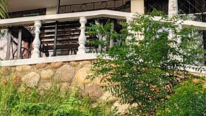 A multi-story building with stone and concrete architecture, featuring balconies with railings and potted plants. - Encantadora casa de 4 alcobas con WIFI (Tocaima)