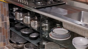 A kitchen with a gas stove, shelves with pots and pans, a sink, and a window with a view of trees. - Encantadora casa de 4 alcobas con WIFI (Tocaima)