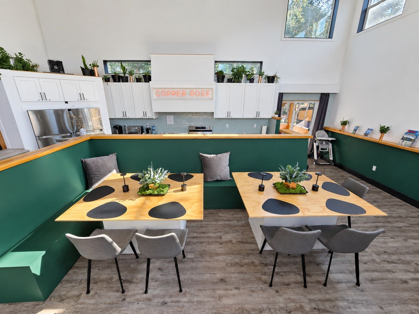 Une cuisine moderne avec des meubles blancs, un coin café et un espace détente avec des tables et des chaises.