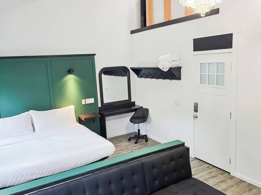 A modern bedroom with a bed, a bench, a desk, and a chair.