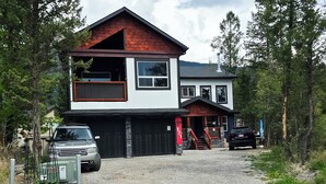 A two-story house with a garage, a covered porch, and a gravel driveway. - Copper Rose Retreat B&B (Invermere)