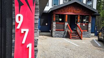 Welcome to a two-story building with a distinctive red and black sign, featuring a prominent staircase and a well-manicured lawn.