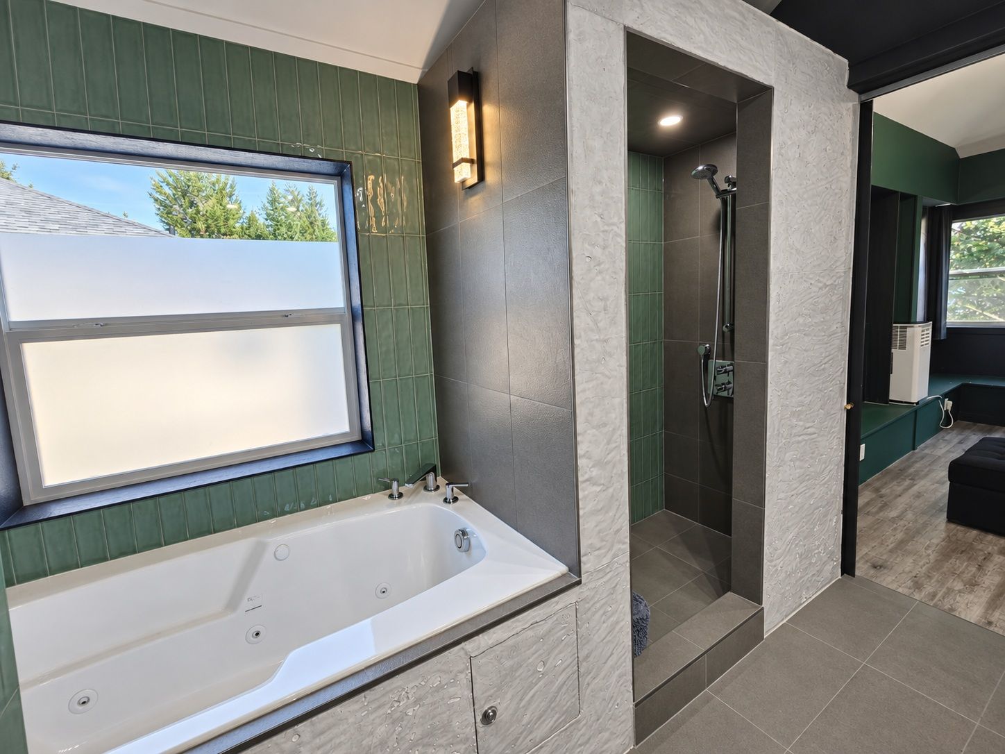 A modern bathroom with a bathtub, shower, and a window providing a view of the outdoors.