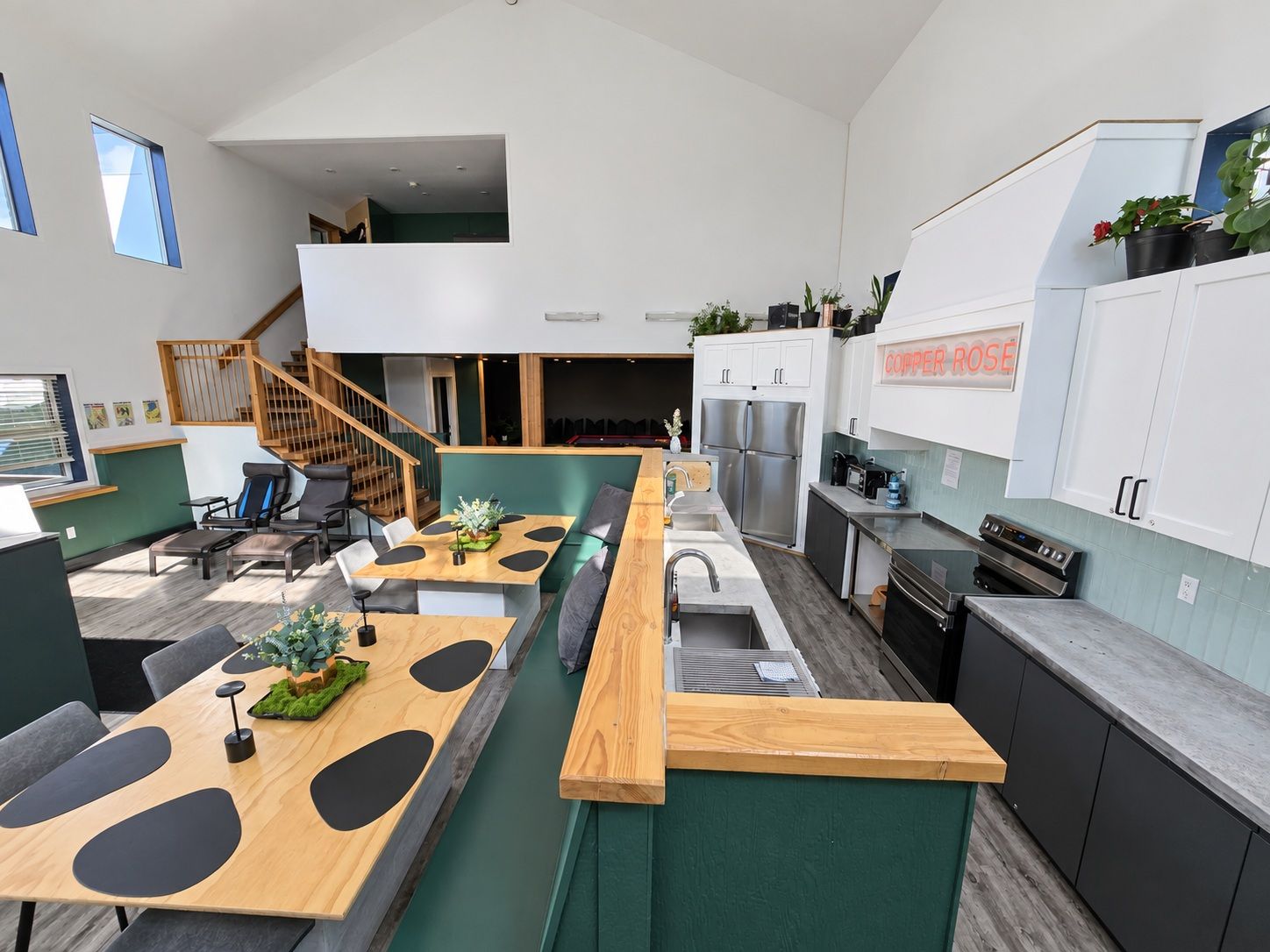Una cocina moderna con una isla central, electrodomésticos integrados y un comedor con una escalera que sube a un nivel superior.